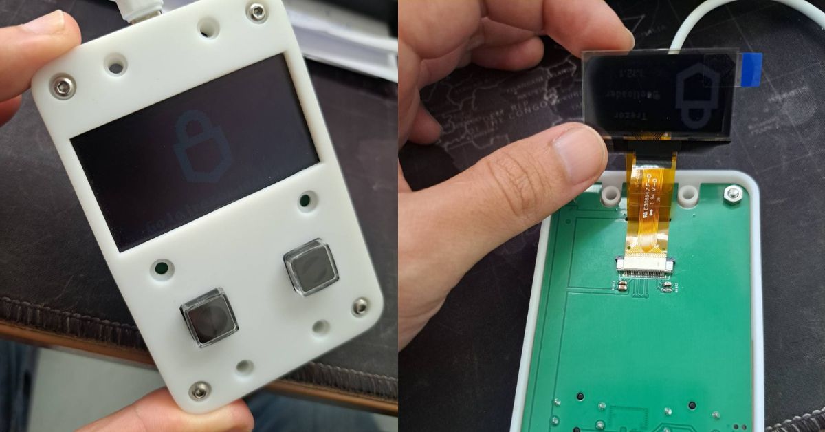 A PHYLAX prototype with the OLED lit up, and the display module connected by ribbon cable during bench testing